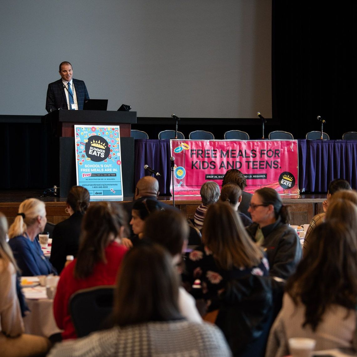 Robert M. Leshin, Director of the Office for Food and Nutrition Programs at the Department of Elementary and Secondary Education (DESE), address conference attendees while on stage.
