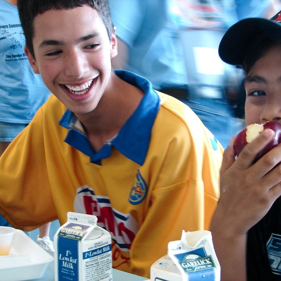 Two kids enjoy a healthy school meal.