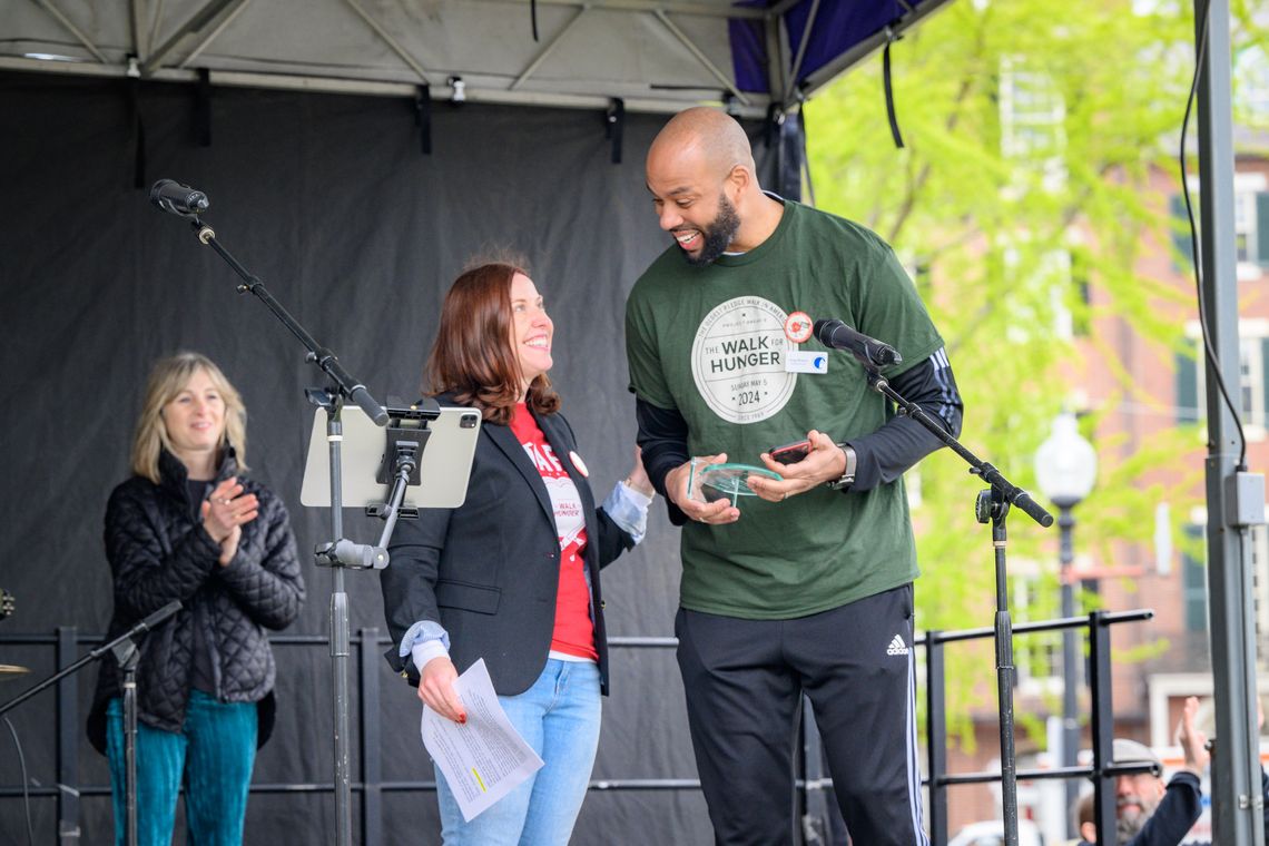 Greg Wilmot receives Patrick Hughes Award for Social Justice from Erin Mcaleer on the stage at the 2024 Walk for Hunger