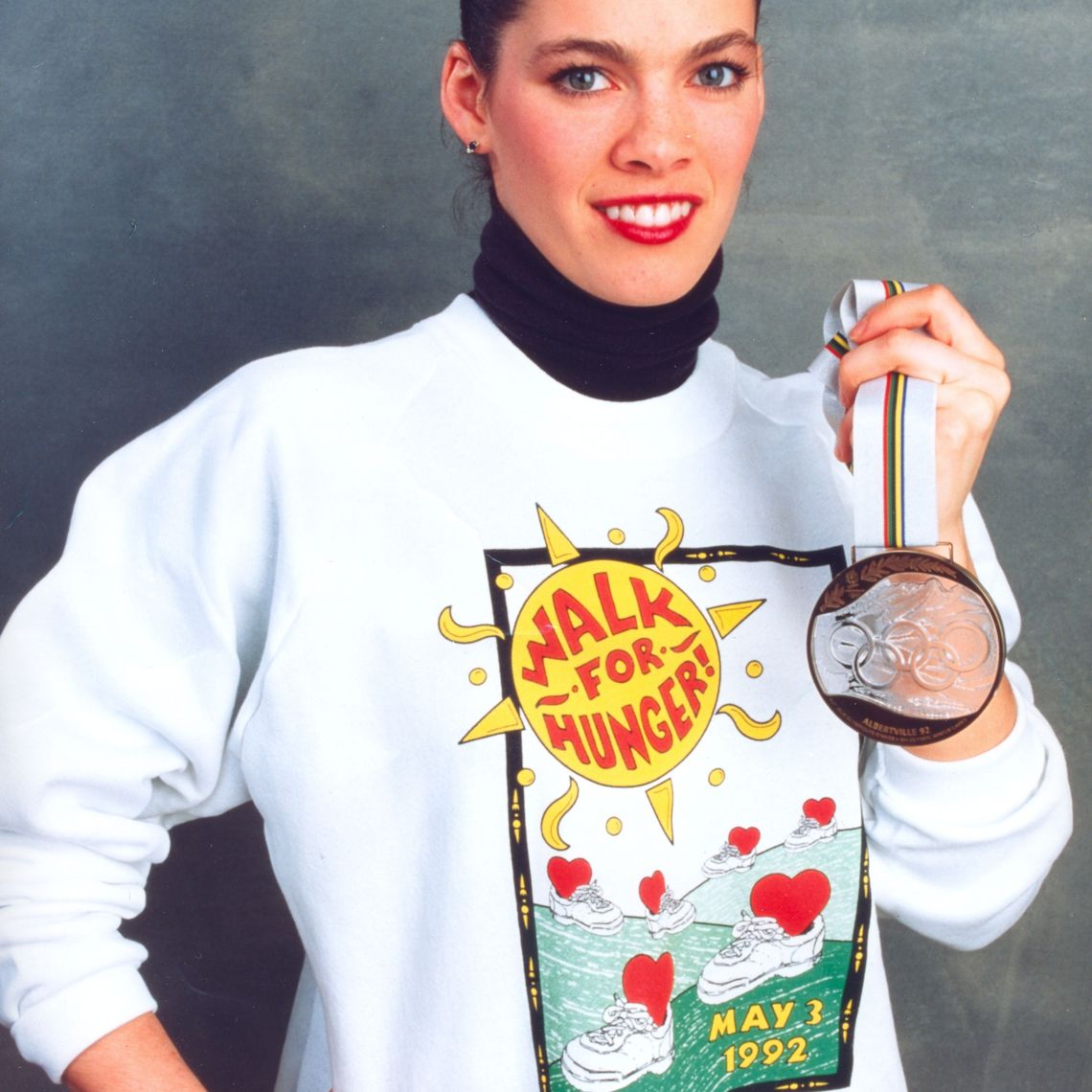 Nancy Kerrigan, Olympic figure skater, poses with her bronze medal from the 1992 Olympics, wearing a Walk for Hunger sweatshirt.