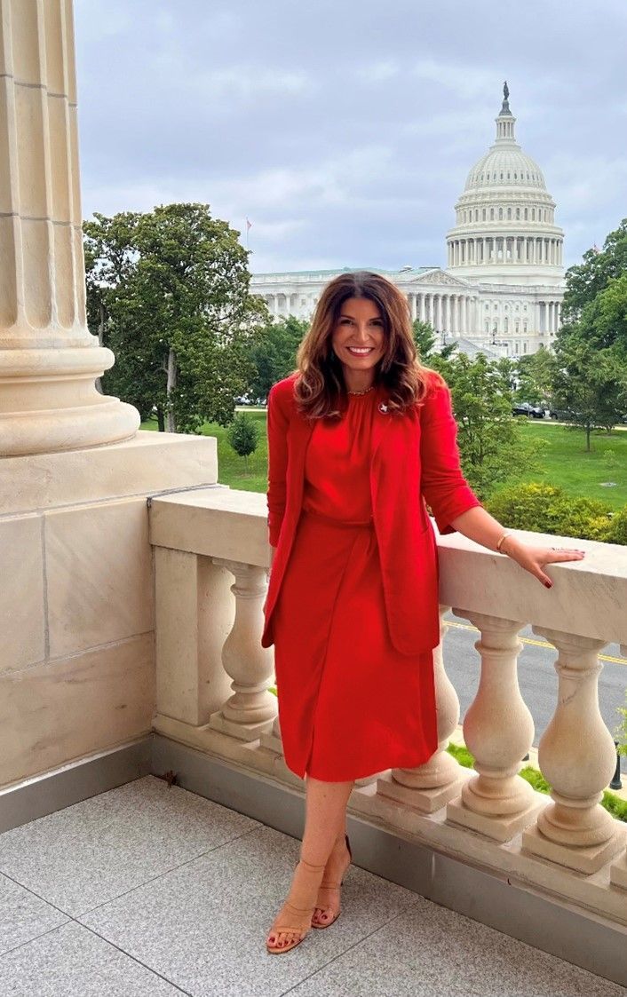 woman in red outfit standing in front of U.S. capitol building