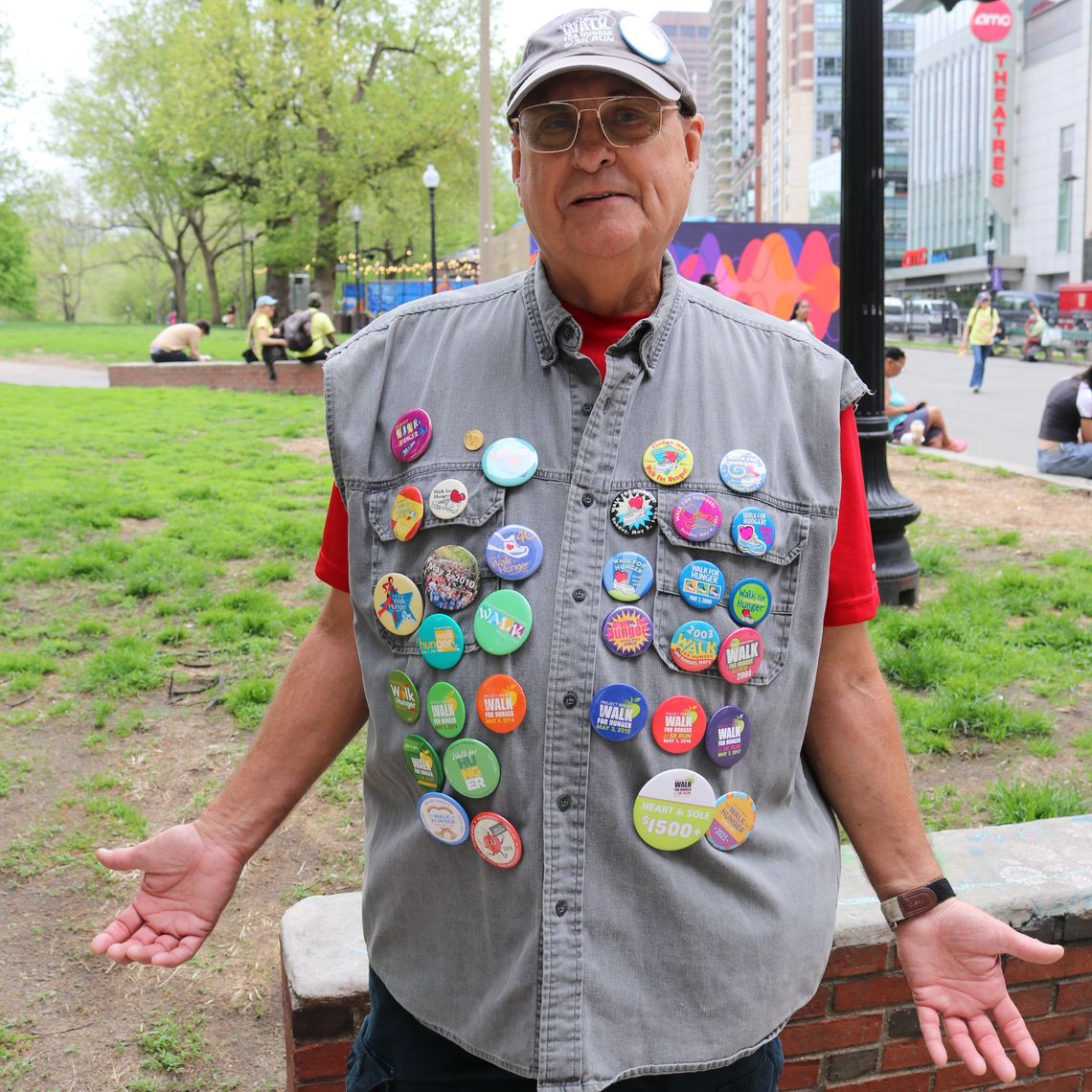 A man sports a vest decked out with Walk for Hunger buttons.