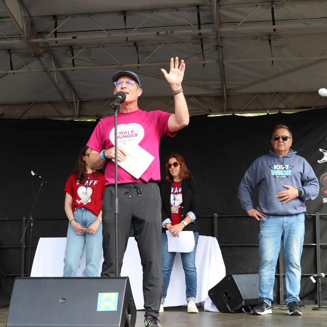 A man wearing a Walk for Hunger shirt announced a $20,000 match on stage.