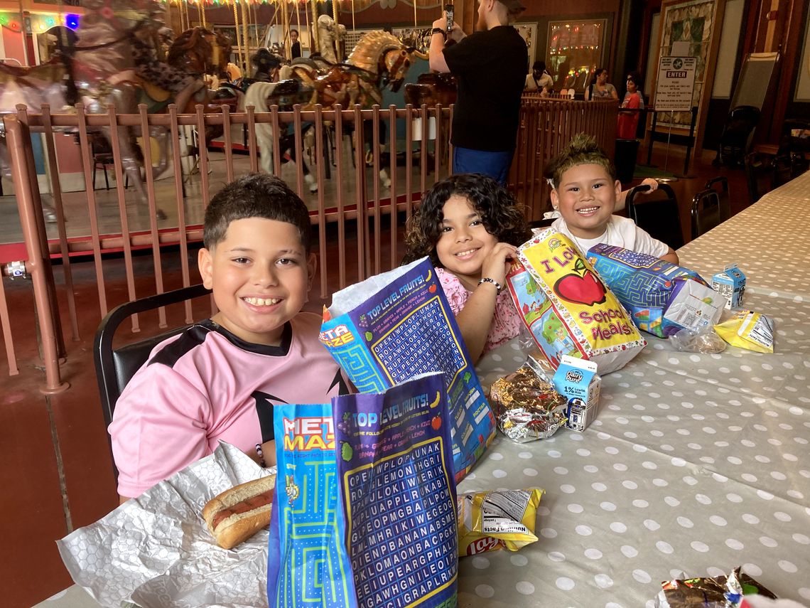 3 kids smiling with free lunches from Summer Eats