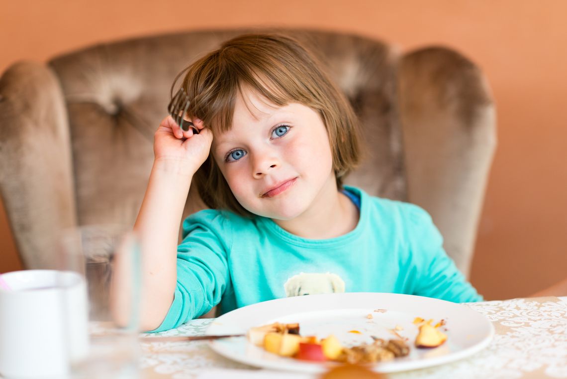 Adorable little girl eating pancake and fruits for a breakfast in restaurant. Healthy eating concept
