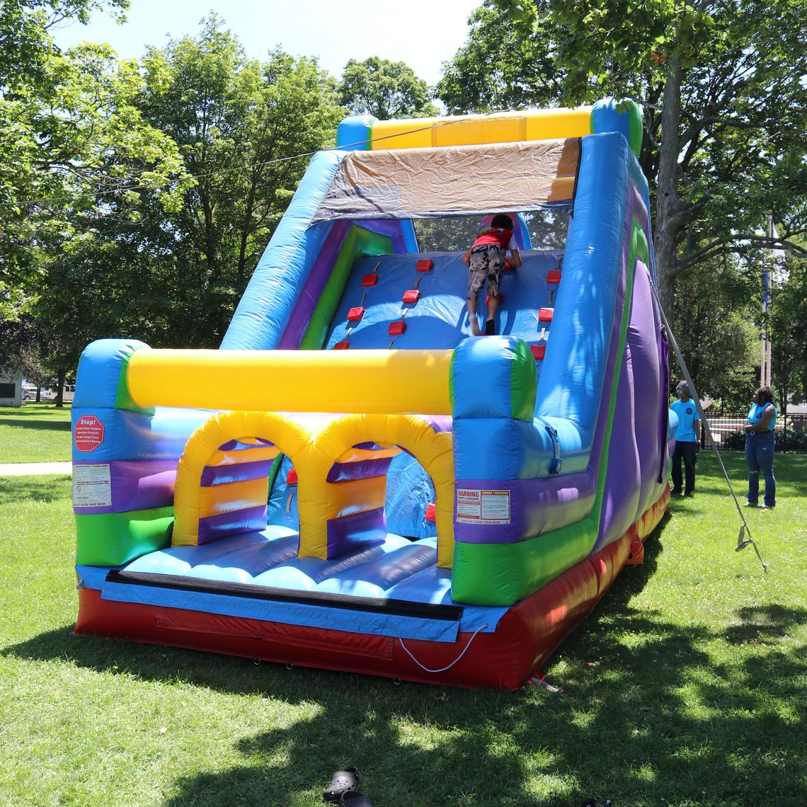 A kid climbs an inflatable slide at the Waltham Summer Eats kickoff.